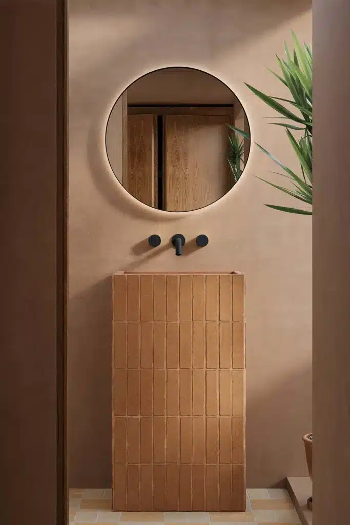 Small-Bathroom-Design-Ideas-back-lit-round-mirror-terracotta-tiled-pedestal-basin-earthy-interior